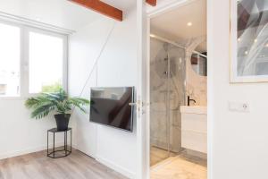 a bathroom with a tv on the wall next to a shower at Hoog e in Eindhoven +9 photos