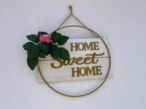 a sign that reads home sweet home with a flower at Home Sweet Home in Skopelos Town
