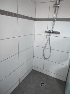 a shower with a hose in a white tiled bathroom at Maison jardin calme in Lambersart +15 photos