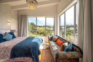 a bedroom with a bed and a couch and a window at Vineyard Magic, Onetangi in Onetangi