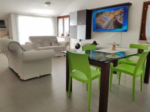 a living room with a table and green chairs at Villa del Mar Country Loft in Sassari