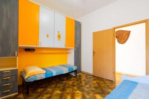 1 dormitorio con armarios de color naranja y blanco y 1 cama en Casa Antony Punta Prosciutto, en Punta Prosciutto