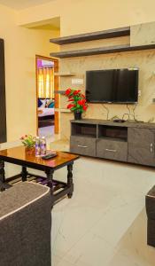 sala de estar con mesa y TV en la pared en S V IDEAL HOMESTAY -2BHK SERVICE APARTMENTS-AC Bedrooms, Premium Amities, Near to Airport, en Tirupati