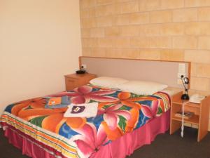 a bedroom with a bed with a colorful comforter at Country View Motel Ilbilbie in Ilbilbie