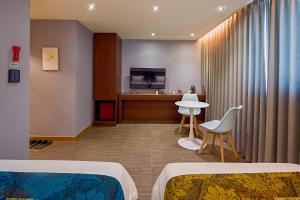 a hotel room with two beds and a table and a television at Namsan Hill Hotel in Seoul