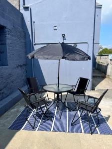 a table and chairs with an umbrella on a patio at Ty Noah- Home In The Heart Of Pembrokeshire in Milford Haven