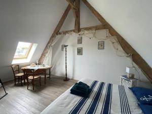 a bedroom with a bed and a table in a room at Nid de pie Grand duplex lumineux cadre verdoyant calme à 5 mn de la mer près Port en Bessin, Bayeux, Omaha Beach, in Commes