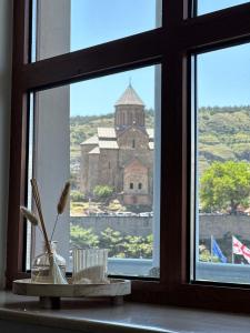 een raam met uitzicht op een kerk die er doorheen kijkt bij Hotel Europe plaza in Tbilisi City