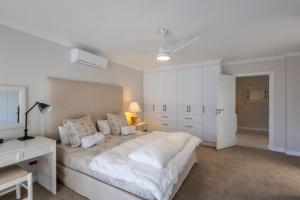 Un dormitorio blanco con una cama grande y un escritorio. en Sun Centre 9, en Plettenberg Bay