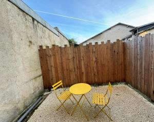 une table jaune et deux chaises devant une clôture dans l'établissement La Sout à découverte, à La Souterraine