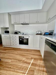 a kitchen with white cabinets and a wooden floor at Magnolia Little Gem in Alstonville +10 photos