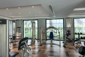 einen Fitnessraum mit Laufbändern und Maschinen in einem Zimmer mit Fenstern in der Unterkunft StoneTree - Furnished Studio - Amazing View in Dubai