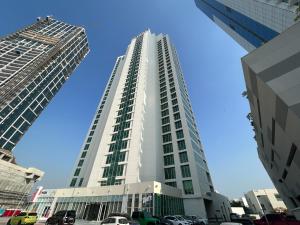 wysoki biały budynek z samochodami zaparkowanymi na parkingu w obiekcie StoneTree - Furnished Studio - Amazing View w Dubaju