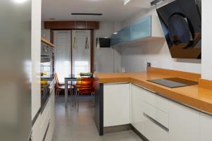 a kitchen with white cabinets and a table with chairs at Kato kale in Bermeo