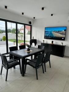 a dining room with a table and chairs and a tv at Reshkov Pool Apartments in Gevgelija