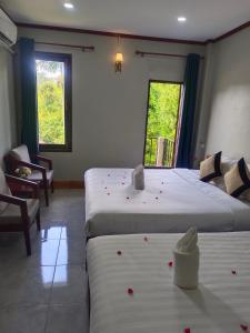 - 2 lits dans une chambre ornée de fleurs rouges dans l'établissement Vang Vieng Champa Hotel, à Vang Vieng