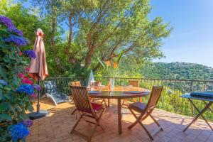 a patio with a table and chairs and an umbrella at Vue mer dans les collines Cavalaire in Cavalaire-sur-Mer