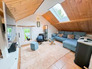 ein Wohnzimmer mit einem blauen Sofa und einigen Fenstern in der Unterkunft Altes Backhaus in der Eifel in Feuerscheid