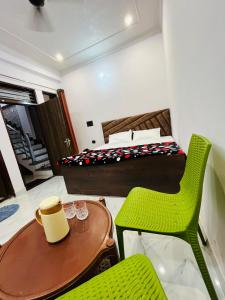 a room with a bed and a table and a green chair at Vinayak Homestay in Mathura