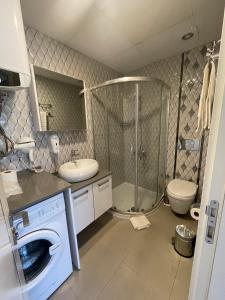 a bathroom with a washing machine and a sink and a toilet at Sigacik Marina Apart Hotel in Siğacık