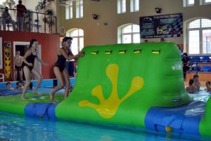 two girls are jumping into a swimming pool at Pokoje w Gołdapi in Gołdap