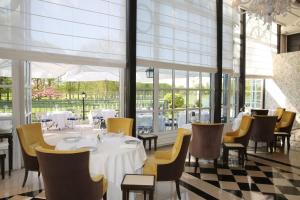 uma sala de jantar com mesa, cadeiras e janelas em Waldorf Astoria Versailles - Trianon Palace em Versalhes