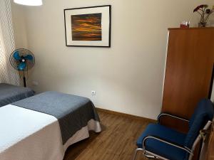 een slaapkamer met een bed en een blauwe stoel bij Amplio Nervion Santa Justa ideal familias y grupos in Sevilla