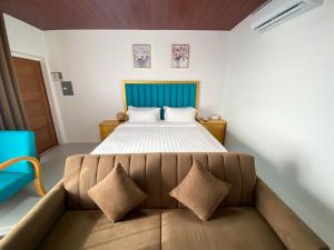 een slaapkamer met een bed en een bank met kussens bij Q Beach Resort in Cabangan