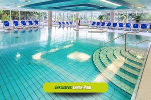 einen Innenpool mit blauen Stühlen in einem Gebäude in der Unterkunft AHORN Panorama Hotel Oberhof in Oberhof
