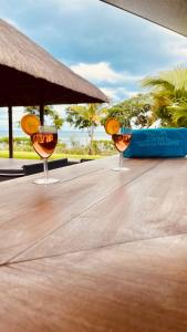 two glasses of wine sitting on a wooden table at Villa de luxe La Paillotte in Petite Case Noyale