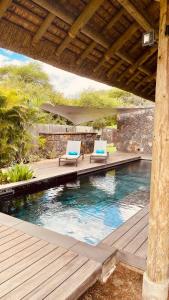 two chairs sitting on a deck next to a swimming pool at Villa de luxe La Paillotte in Petite Case Noyale