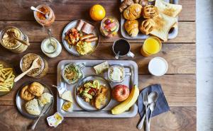 a wooden table with plates of breakfast food on it at MOXY Osaka Honmachi by Marriott in Osaka