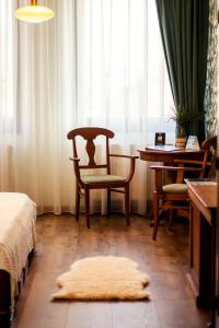 une chambre avec une chaise, une table et une fenêtre dans l'établissement Septimia Hotels & Spa Resort, à Odorheiu Secuiesc
