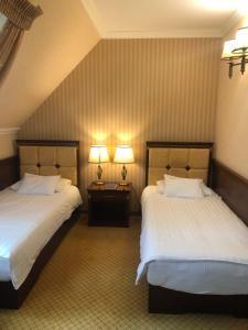 two beds in a hotel room with two lamps at Villa Hotel in Debrecen