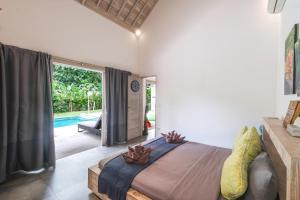 a bedroom with a large bed and a pool at Villa Alexandra Bingin in Uluwatu