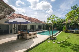 a backyard with a swimming pool and an umbrella at Villa Alexandra Bingin in Uluwatu