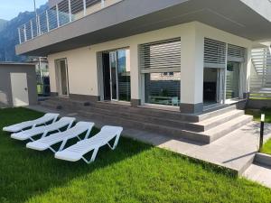 a row of white lounge chairs in the grass in front of a building at San Paolo in Marone +1 photo