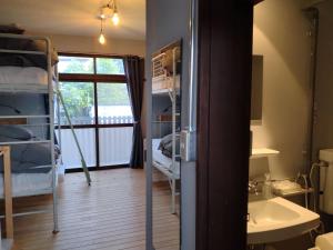 a room with bunk beds and a sink and a window at Toyako Guest House Ponkotan in Lake Toya