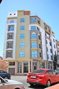 a red car parked in front of a hotel at Hotel La Place in El Jadida