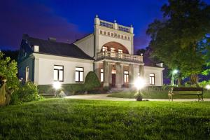 a large white house at night with lights at Agropark - Dworek pod Lipą in Sobków