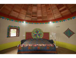 Rann Chandni Resort, Kutch, Bhuj في Bherandiāla: غرفة نوم مع سرير مع لحاف جميل