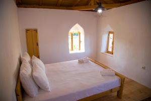 een slaapkamer met een wit bed met kussens en 2 ramen bij Old Tower in Stolac