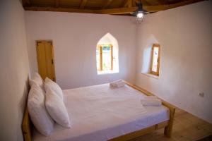 a bedroom with a white bed with pillows and two windows at Old Tower in Stolac