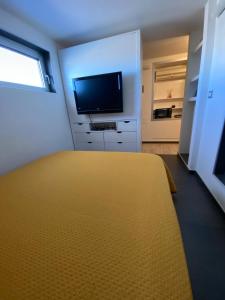 Una sala de estar con una gran cama amarilla y un televisor de pantalla plana. en Attico Tra Cielo e Mare, en Margherita di Savoia