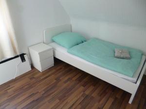 Cette chambre comprend un lit avec des draps verts et du parquet. dans l'établissement Nice Apartment in Vöhringen, à Vöhringen