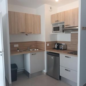 a small kitchen with wooden cabinets and a sink at Cosy Diem Cap d'Agde in Cap d'Agde