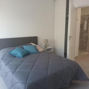 a large bed with blue pillows in a bedroom at Cosy Diem Cap d'Agde in Cap d'Agde
