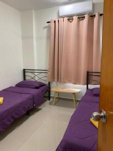 two beds in a room with purple sheets and a curtain at Igo Homestay Subang Airport in Shah Alam