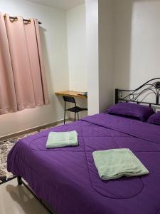 a purple bed with two towels on top of it at Igo Homestay Subang Airport in Shah Alam