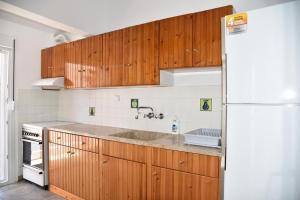 Una cocina con gabinetes de madera y un refrigerador blanco. en Boskos Villa 2, en Nea Vrasna